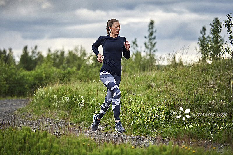 快乐自信的年轻女子奔跑在冰岛南部一条崎岖的道路上图片素材