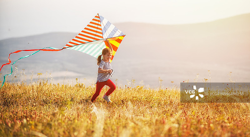 快乐的小女孩和风筝在日落户外图片素材