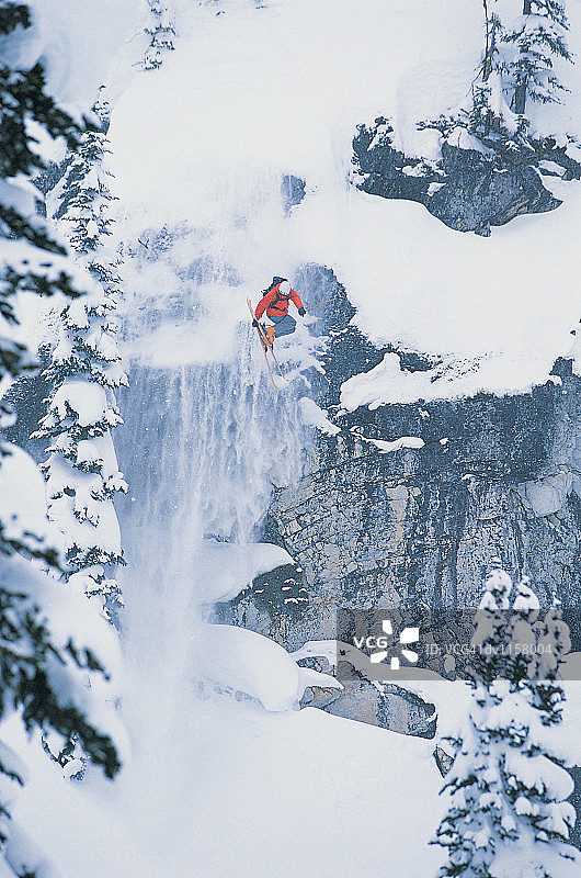 滑雪者跳半空中从一个陡峭的岩石面在森林图片素材