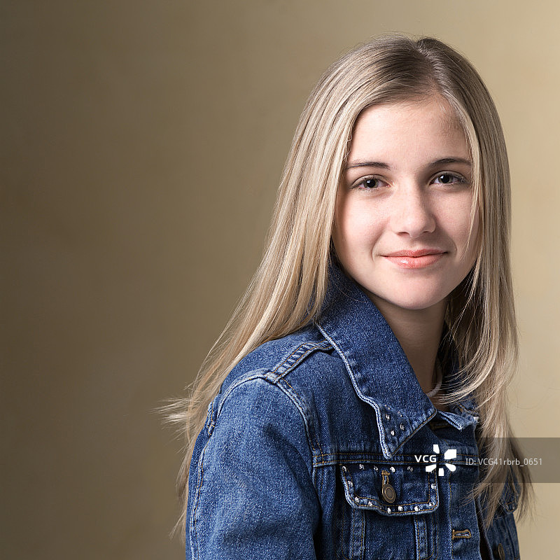 一个金发少女的肖像在一个牛仔夹克，因为她微笑图片素材