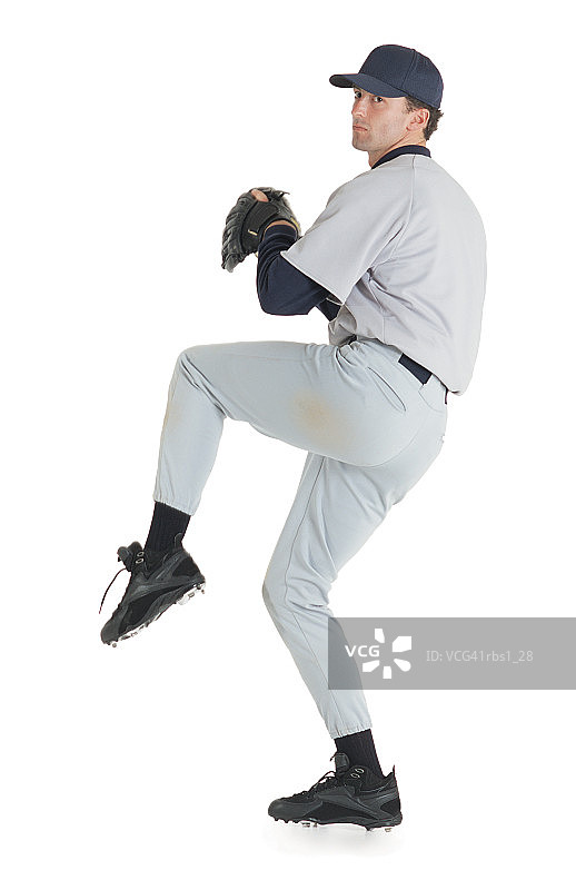 一名身穿白色棒球服的白人男子戴着棒球帽和手套，站在一顶棒球帽上准备投球图片素材