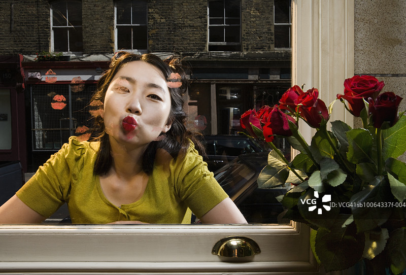 年轻女子在窗玻璃上接吻，肖像图片素材