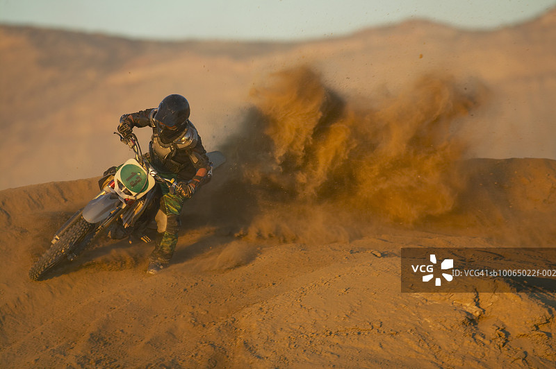 在沙漠地带骑摩托车，摩托车扬起尘土图片素材