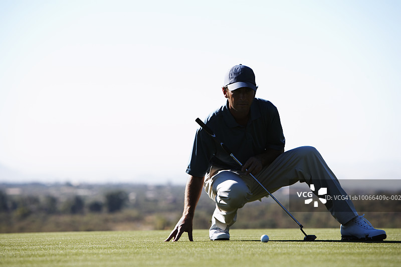 男高尔夫球手在高尔夫球场上推杆图片素材