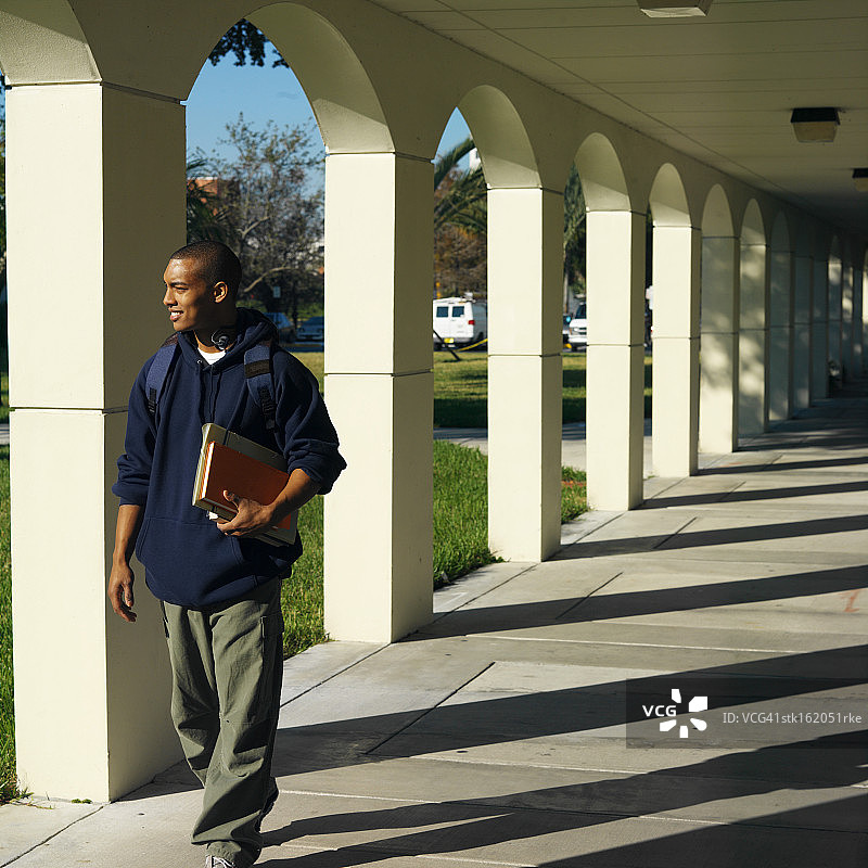 一个年轻人走在学校的走廊上图片素材