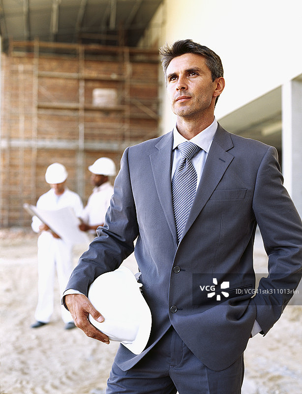 一个建筑师拿着安全帽在建筑工地的特写图片素材