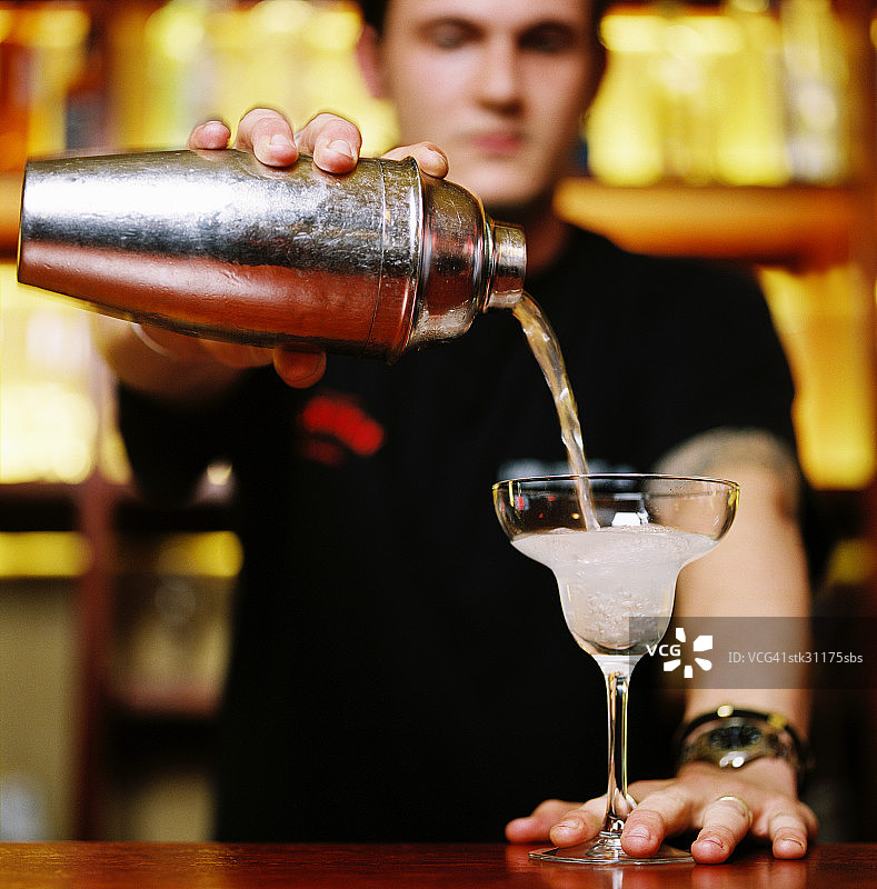 一个调酒师用调酒器倒鸡尾酒的肖像图片素材