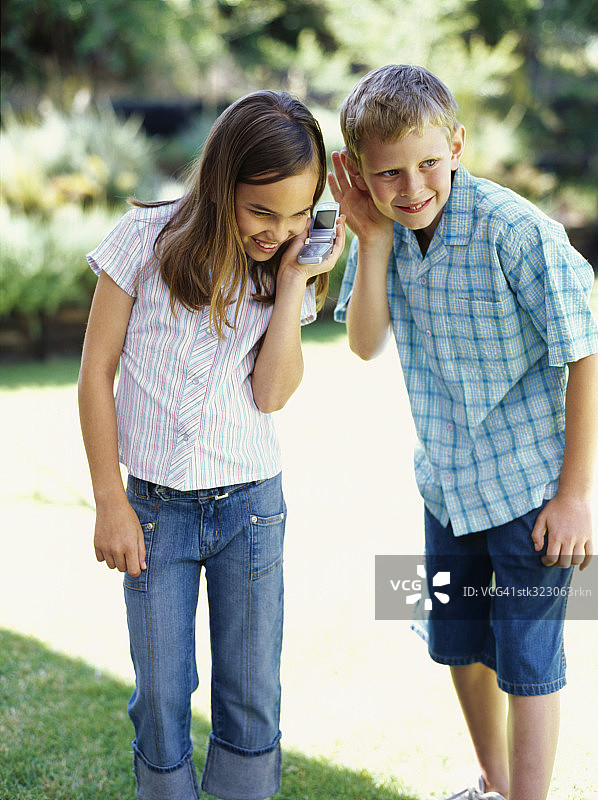 一个男孩和一个女孩在听手机图片素材