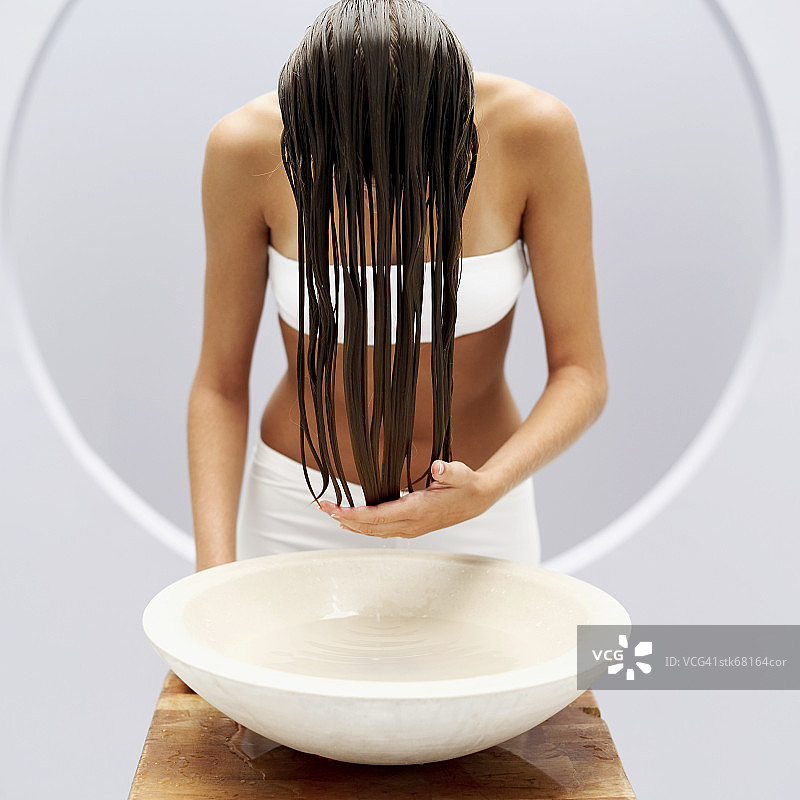 一个女人用一盆水洗头图片素材