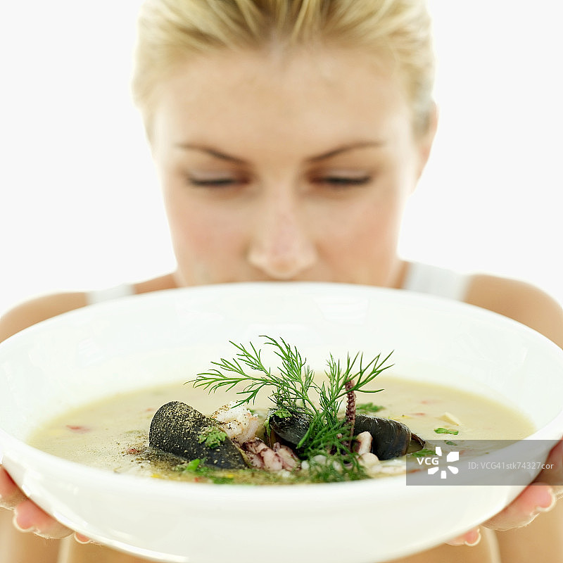 一个女人手里拿着一碗海鲜汤的特写图片素材