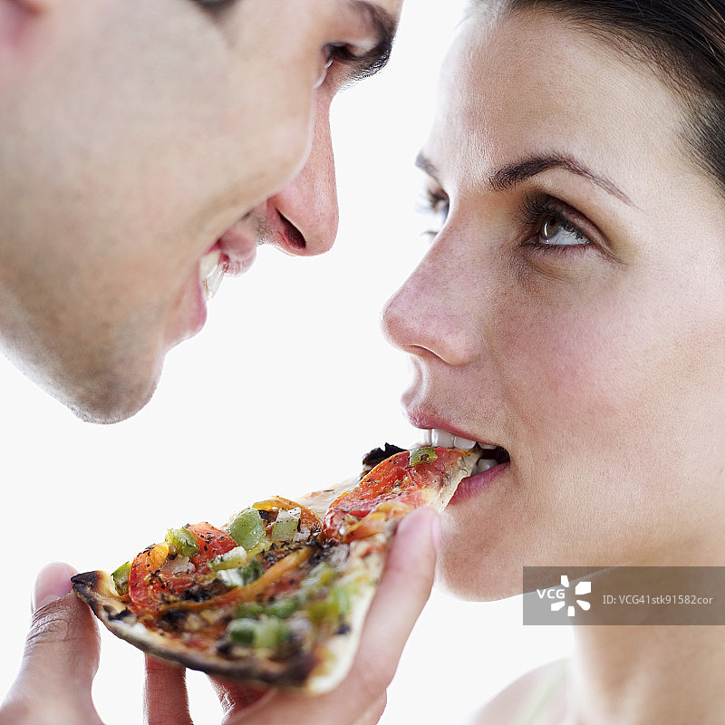 一个男人喂一个女人一片披萨的特写图片素材