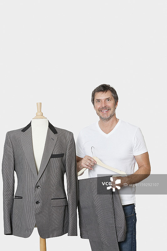 肖像的成熟男子站在旁边的裁缝的假人在灰色的背景图片素材