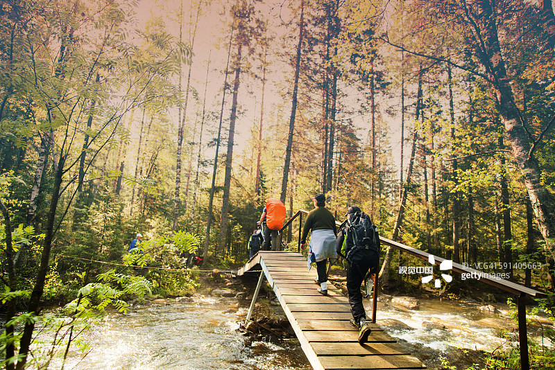 背包客在森林里的桥上徒步旅行图片素材