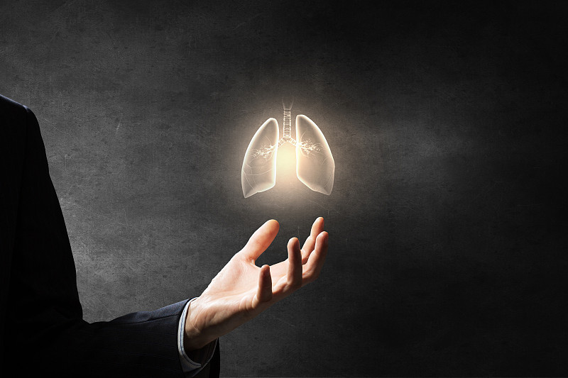 健康的肺和呼吸。男性的手在黑暗的背景持有肺符号图片下载