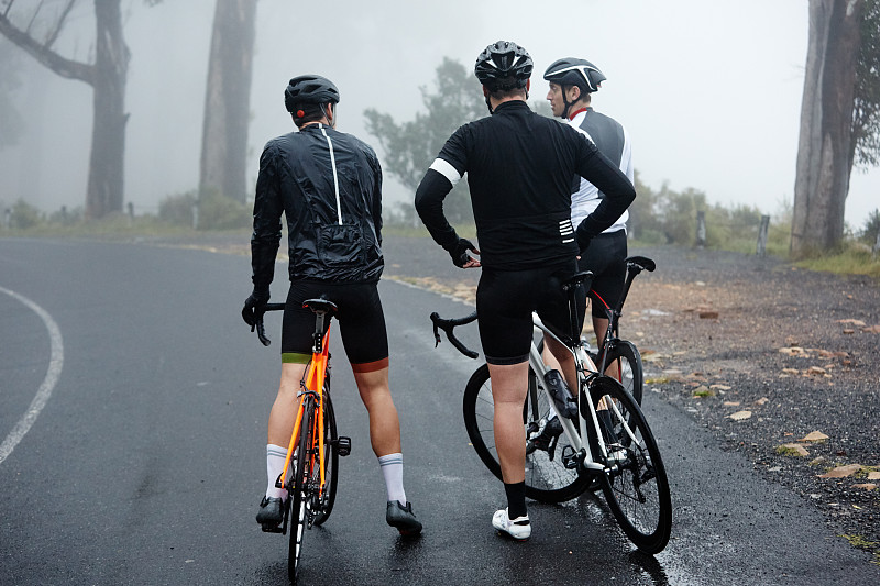 男性骑自行车的朋友们正在潮湿的路面上休息图片下载