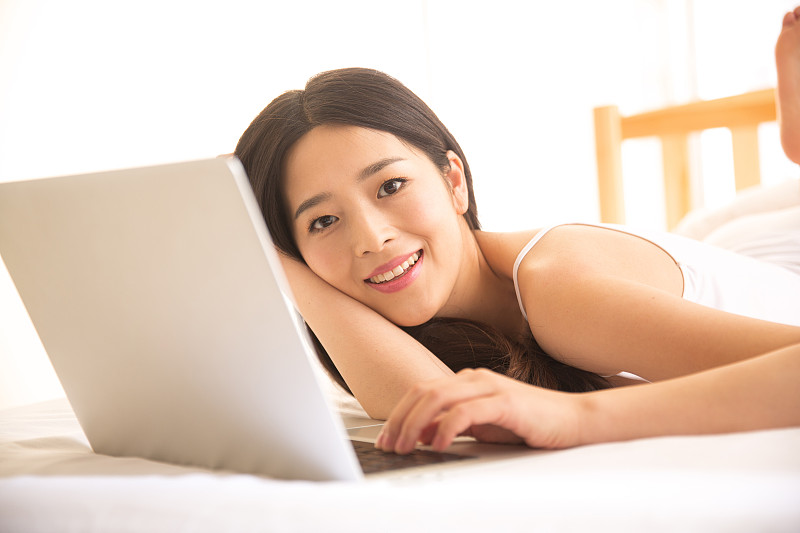 青年女人在卧室使用电脑图片素材