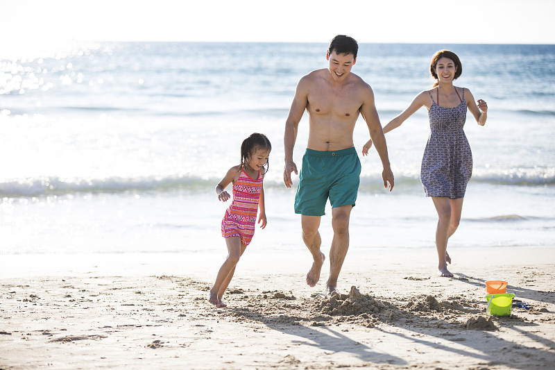 快乐的年轻家庭在沙滩奔跑图片下载