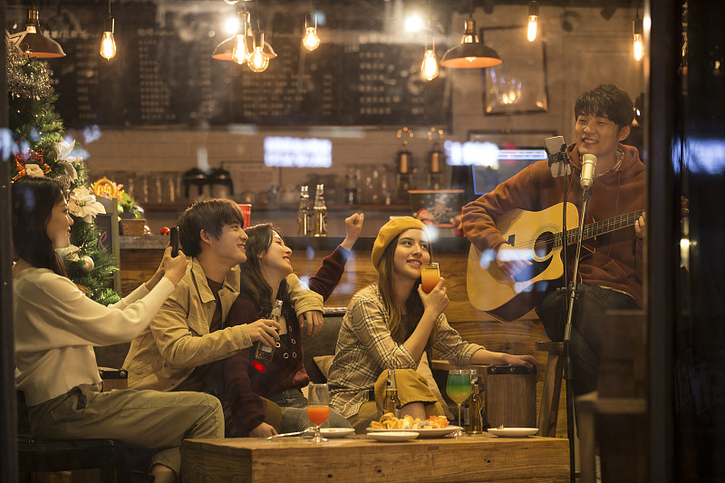 五个青年男女在酒吧弹吉他唱歌喝酒一起欢度圣诞节平安夜图片下载