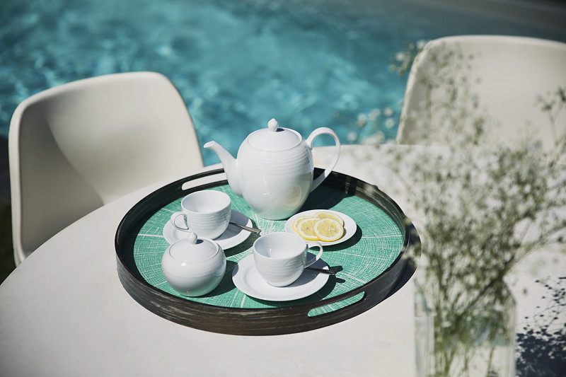 茶具放在阳光充足的池畔露台桌上图片下载