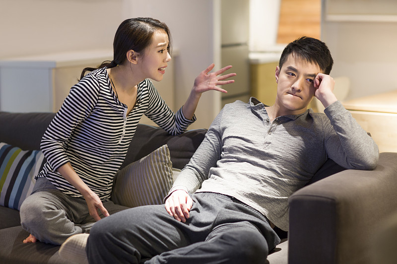 年轻情侣在客厅沙发上争吵图片下载