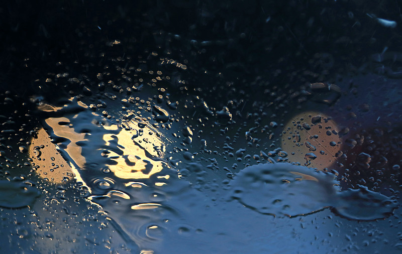 大雨时透过挡风玻璃看到的雨滴和交通灯图片下载
