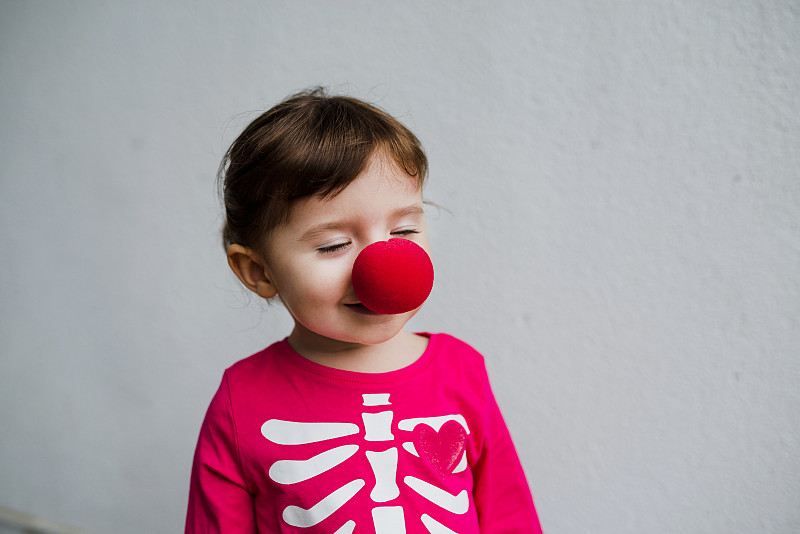 万圣节的宝贝女孩穿着骷髅服装和小丑红鼻子图片下载