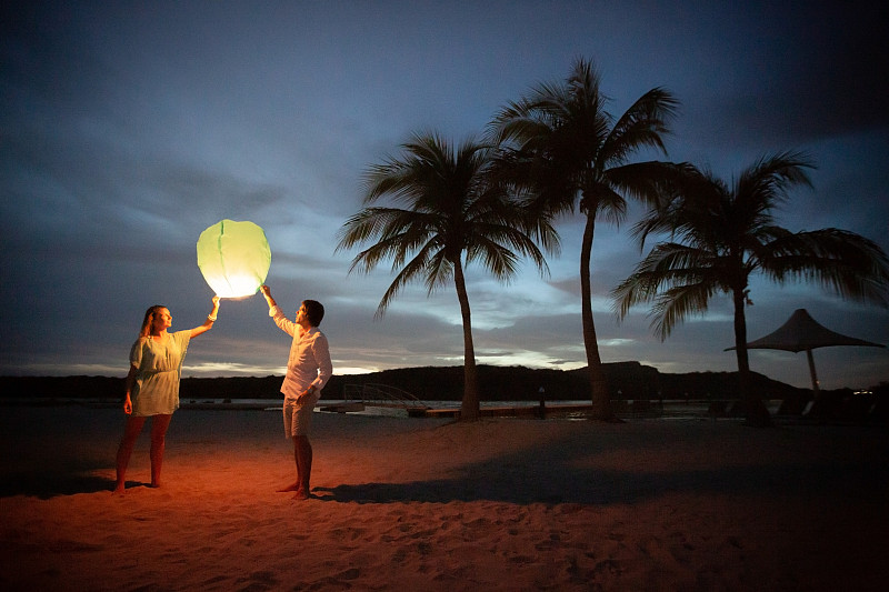 日落时分，一对夫妇在海滩上提着灯笼图片下载