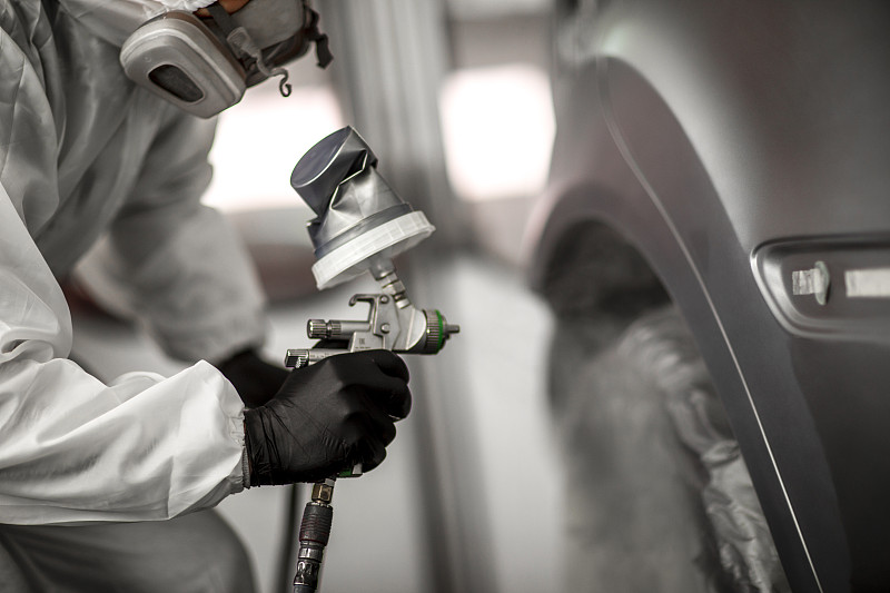 涂装技术员在车身修理厂涂装车间里，在汽车上涂抹一层涂料图片下载