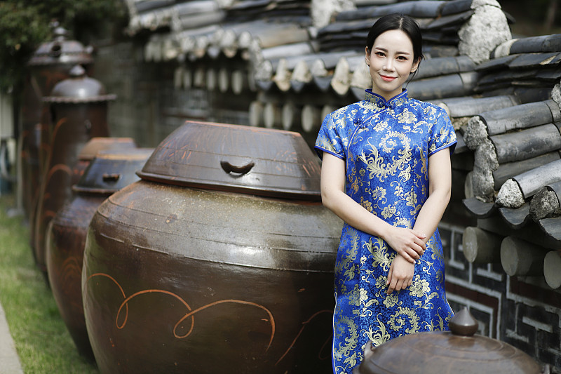 穿着旗袍的女子站在长穴台，韩国传统的坛子旁图片素材