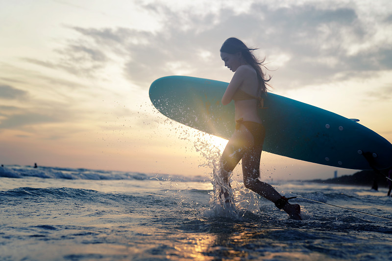 美丽的亚洲女子冲浪者在比基尼享受夏天的海滩冲浪板。图片素材