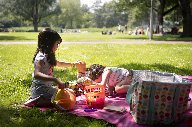 两个女孩在公园的野餐毯上图片下载