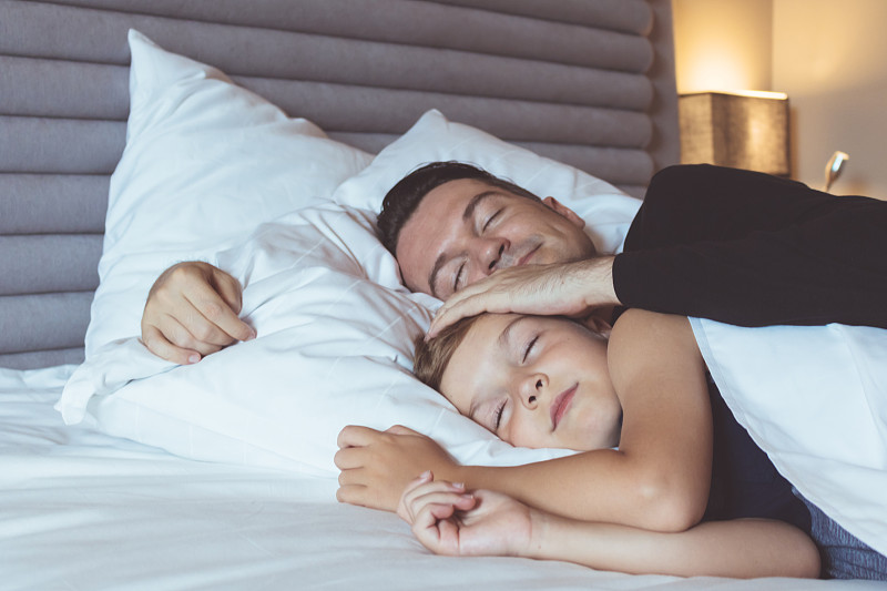 父亲和儿子睡在家里的床上图片素材