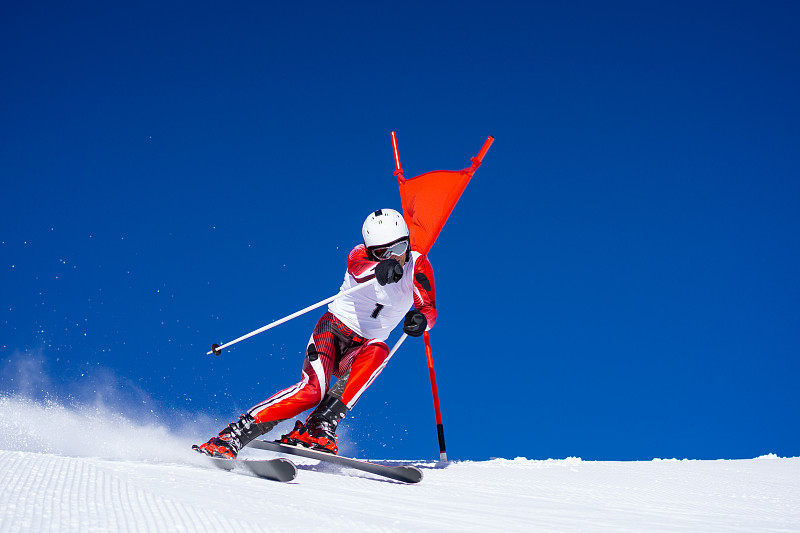 一名职业滑雪者在晴朗的蓝天下触摸滑雪杆图片下载