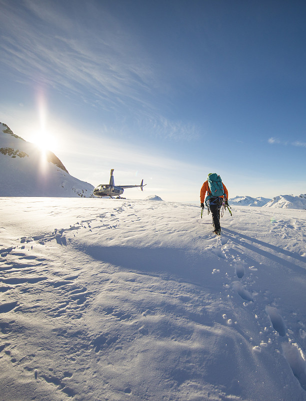 一个登山者接近他的直升机，等待冰川。图片下载