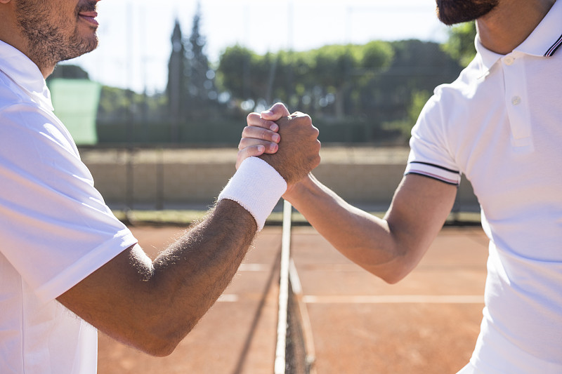 两名网球运动员在网球比赛前握手和微笑的侧视图图片素材