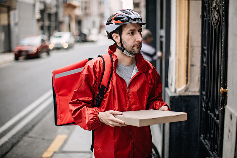 在城市里骑自行车送食物的人图片下载