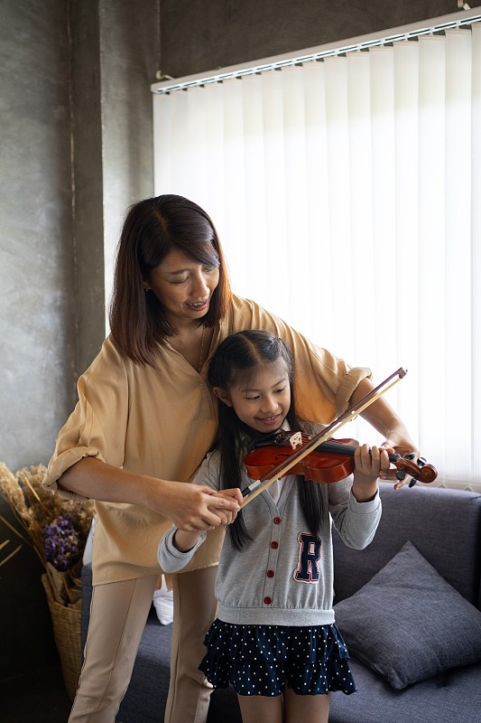 亚洲妇女教小提琴和一个小女孩。图片素材