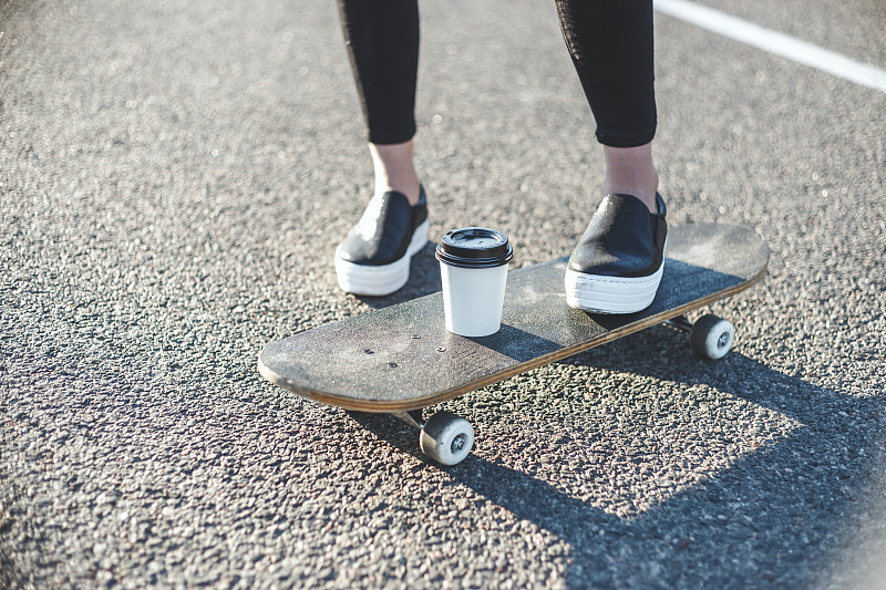 在公路上滑滑板的女人的低段图片下载