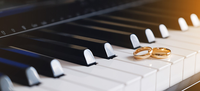 钢琴琴键上放着结婚金戒指。图片下载