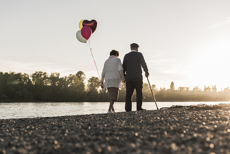 老夫妇与气球漫步在傍晚的河边背影图片下载