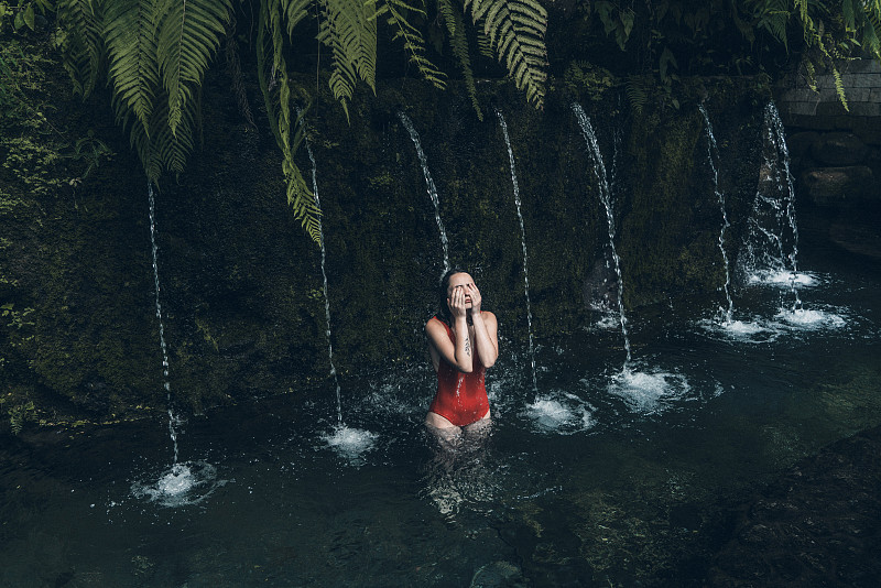 一个女人站在巴厘岛的温泉池里图片下载