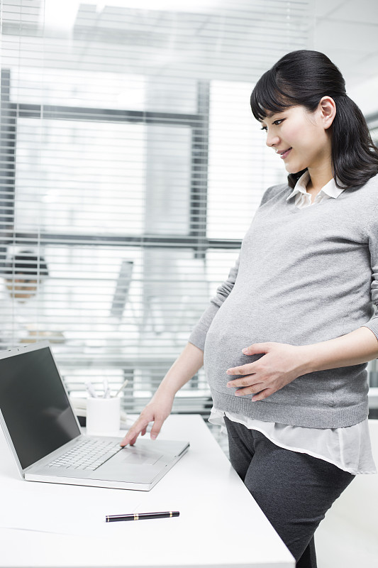 怀孕的商务女士使用笔记本电脑图片素材
