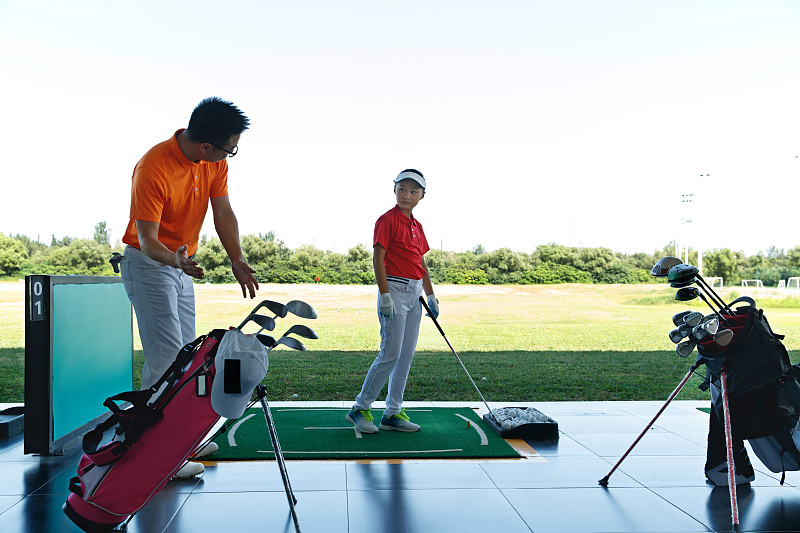 练习场上教练指导儿童打高尔夫图片下载