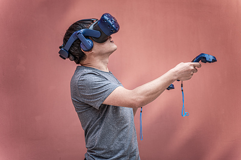 一个中国男人戴着VR虚拟现实眼镜拿着游戏手柄体验图片素材
