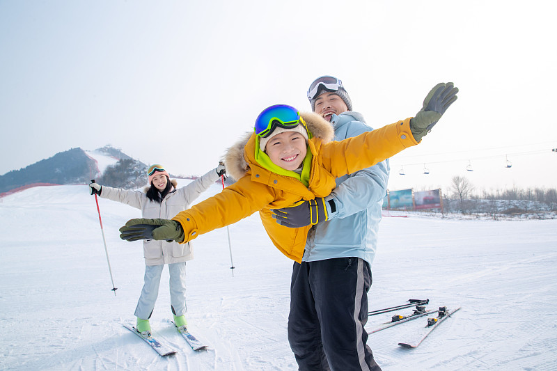 滑雪场上抱着儿子飞的父亲和滑雪的母亲图片素材