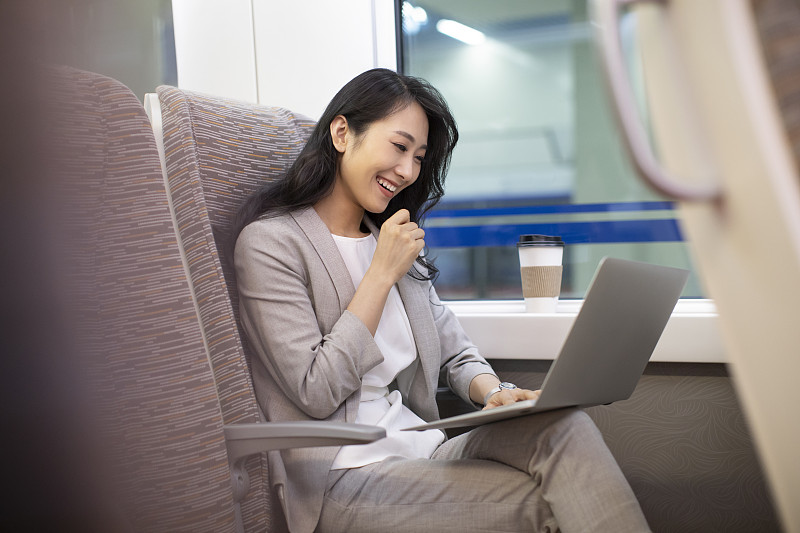 年轻商务女士在高铁上使用笔记本电脑图片素材