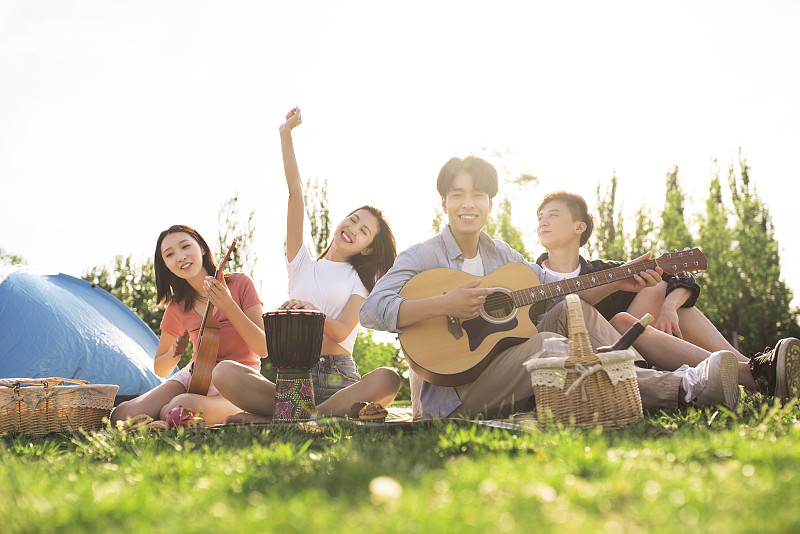 快乐的年轻人在户外野餐演奏音乐图片下载