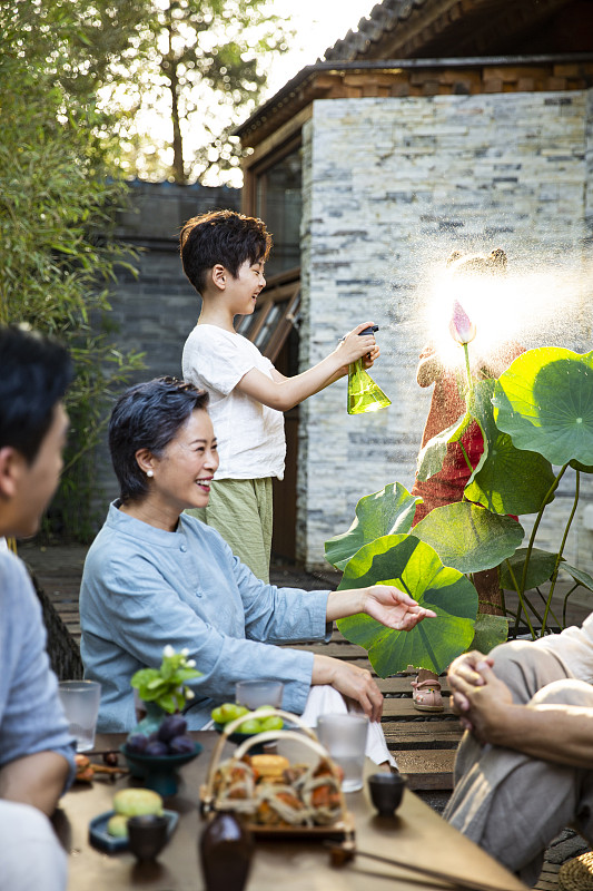 中秋节一家人庭院聚会吃饭、孩子喷水嬉戏玩耍图片素材