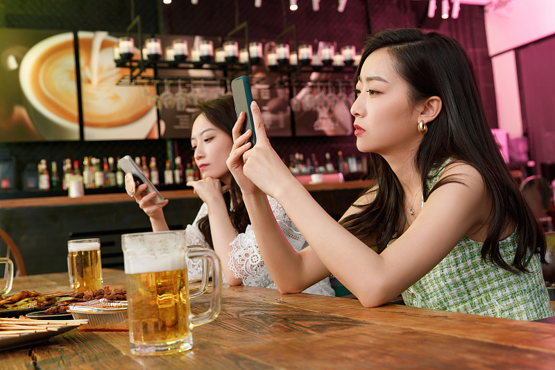 在酒吧里玩手机的青年女人图片素材
