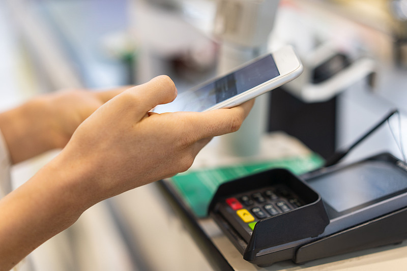 一名女性使用非接触式支付方式在商店用手机付款图片素材